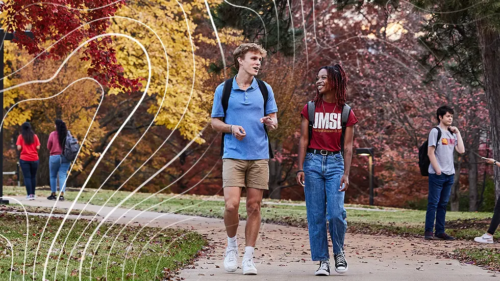 two UMSL students in conversation while walking down sidewalk