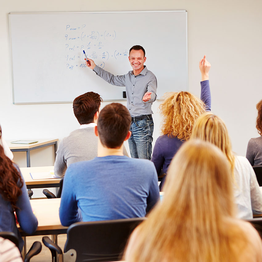 male teacher at a white board in front of a class