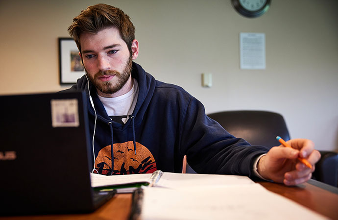 male student with a laptop and a notebook