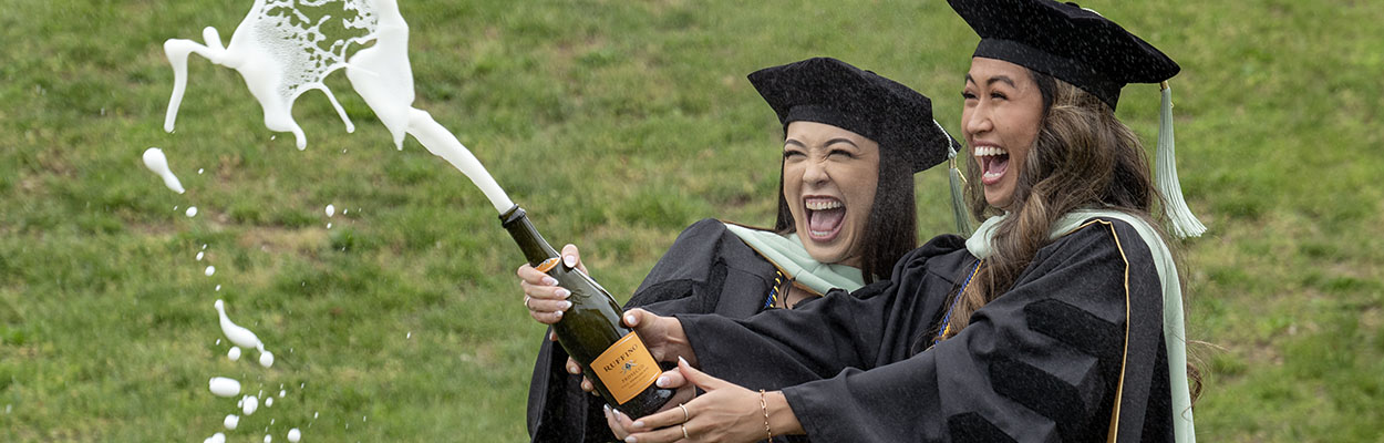 Two graduates with champagne bottle