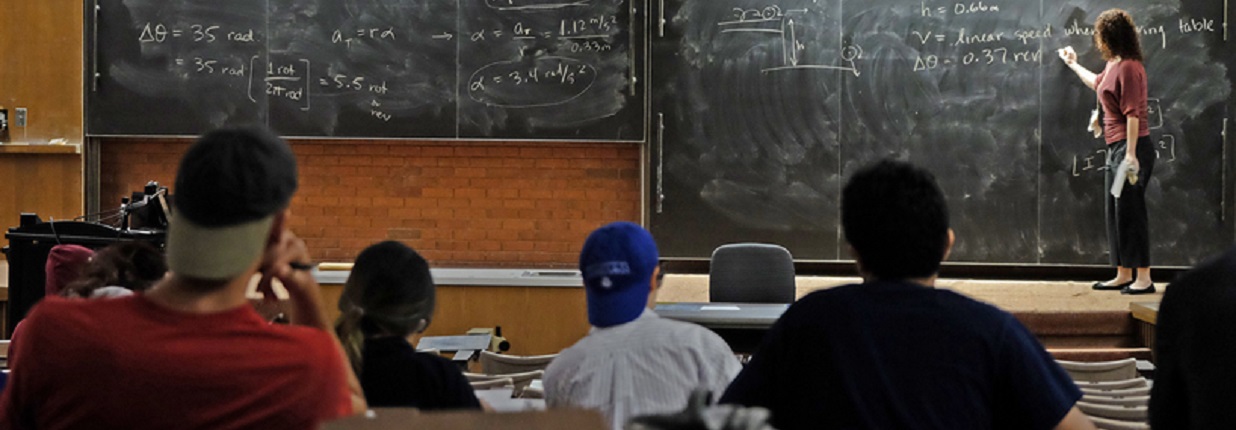 Professor demonstrates a problem using a chalkboard in a class full of students