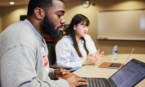 two students at laptops in class