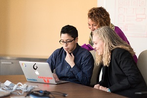 Picture of three people looking at computer