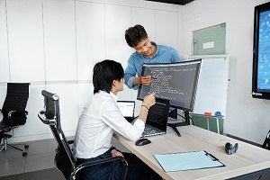 Picture of student sitting at computer with instructor pointing to screen