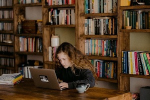 Picture of person in library sitting at table in front of laptop